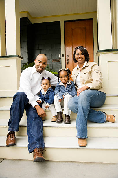 Portrait of a young family sitting on the steps in front of their house.